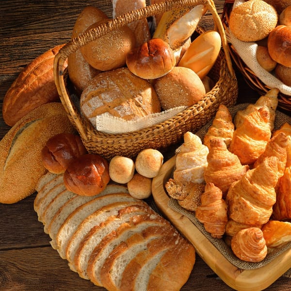 Assortment of fresh Italian breads, rolls, and croissants displayed on a rustic wooden table.